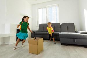 funny kids boy and girl running inside luxury big modern house on moving day, cute children entering exploring new home photo