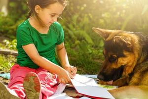 Little girl playing with dog outside, stroking german shepherd lying on porch, leisure of cozy warm happy family in country house photo