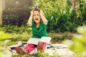 Young girl reading a book while lying in the grass. A girl sits among the many books in the garden. Many books on the grass in the summer garden photo