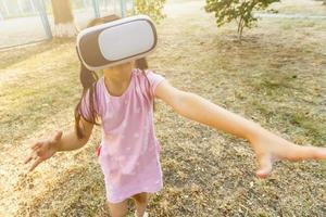 Child with virtual reality headset sitting behind natrue outdoors at home. photo
