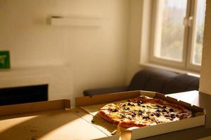 tasty pizza in cardboard box on table photo