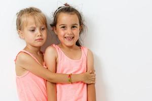 Cute little  American and caucasian girls are keeping hands up, looking at camera and smiling, isolated on a white background photo