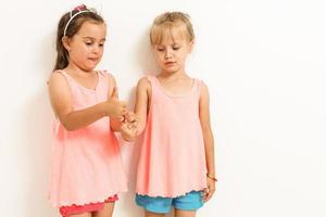 dos linda pequeño muchachas en pie antecedentes en el estudio. verano, divertido, familia y vacaciones concepto. dos Moda hermanas posando foto