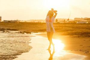 despreocupado mujer bailando en el puesta de sol en el playa. vacaciones vitalidad sano vivo concepto foto