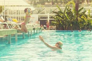 retrato de sonriente hermosa mujer y su pequeño linda hija en Gafas de sol cerca piscina al aire libre foto