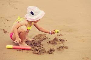 Cute little girl sitting at ocean beach photo