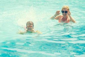 portrait of smiling beautiful woman and her little cute daughter in sunglasses near pool outdoor photo