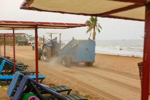 tractor with trailer cleaner cleaning sand on the beach photo