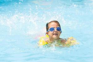 pequeño niña es nadando en el piscina. verano Días festivos y vacaciones concepto foto