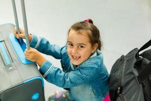 pequeño niña con maleta viaje en el aeropuerto, niños viaje foto