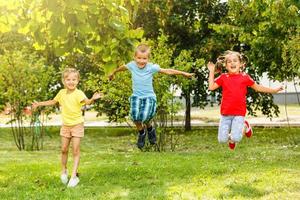 Tres niños a puesta de sol saltando en el parque foto