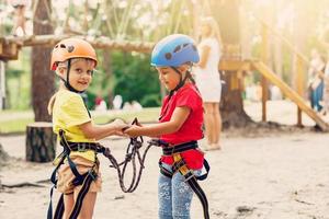 Baby girl with climbing gear in an adventure park are engaged in rock climbing or pass obstacles on the rope road. photo