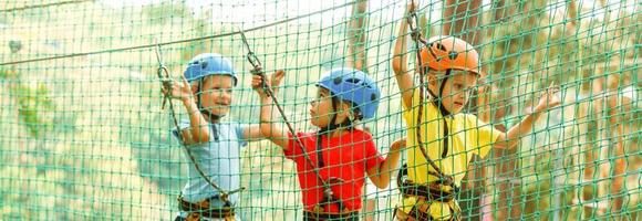 linda niños. chico y niña alpinismo en un cuerda patio de recreo estructura a aventuras parque foto