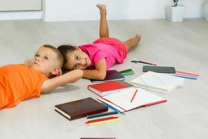 Happy children lying on the floor with group of books photo