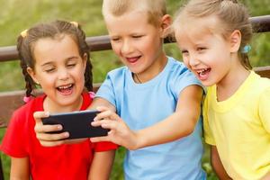 contento niños tomando un selfie con inteligente teléfono. temas amistad, verano y moderno tecnología foto