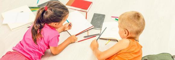 Two cute children draws on floor at home photo