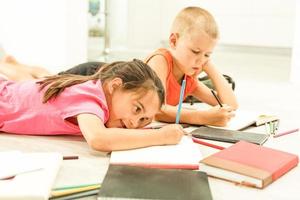 Two cute children draws on floor at home photo