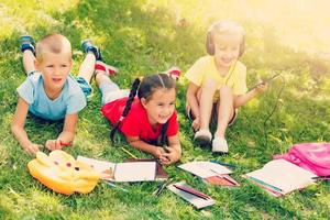 Group of happy children playing outdoors. Kids having fun in spring park. Friends lying on green grass. photo