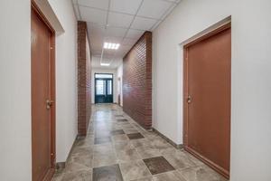 empty long corridor with red brick walls in interior of modern apartments, office or clinic. photo