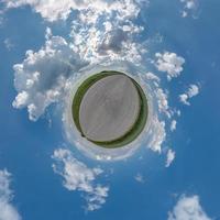 tiny planet in blue overcast evening sky with beautiful clouds with transformation of spherical panorama 360 degrees. Spherical abstract aerial view. Curvature of space. photo