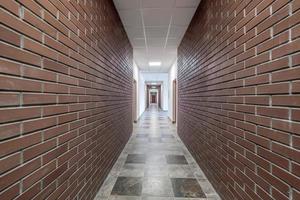 vacío largo corredor con rojo ladrillo paredes en interior de moderno apartamentos, oficina o clínica. foto