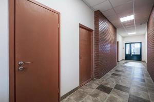 empty long corridor with red brick walls in interior of modern apartments, office or clinic. photo