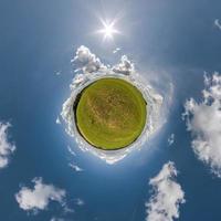 green tiny planet in blue sky with beautiful clouds with transformation of spherical panorama 360 degrees. Curvature of space. photo