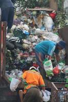 Magelang,Indonesia,2023-Garbage people working together emptying dustbin to dispose of trash with truck loading garbage and dustbin. photo