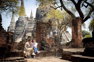 two asian woman holding smart phone in hand sitting in old temple of thailand photo