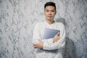 Handsome young smiling is holding a notebook and smiling at office photo