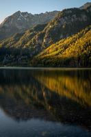 A lake in autumn reflecting the mountains and the livht of the sun photo