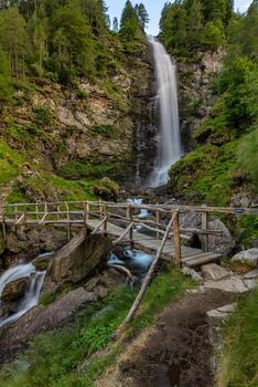 A little wood bridge in front of a waterfall photo