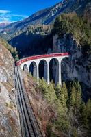 A train going through a tunnel onto a bridge.in the mountains Landwasser viaduct photo