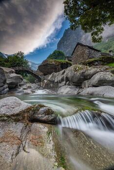 A small stream with a bridge and small stone houses photo