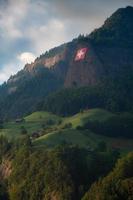 Swiss flag hanging on a steep rock face below is a farm photo