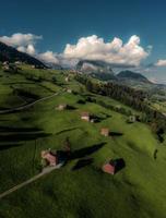 Swiss meadow fields with houses and mountains, in cloudy weather photo