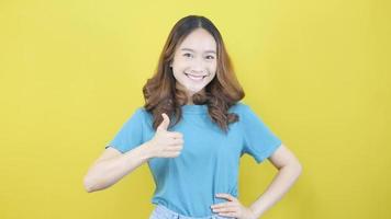 fiducioso asiatico donna mostrando pollici su nel approvazione raccomandazione cioè in piedi su giallo sfondo video