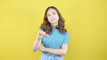 Asian girl looks disgusted to reject the product with a bad smell covering her nose from hatred and cringing standing against a yellow background video