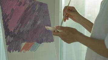 une artiste professionnelle utilise un pinceau dans l'art abstrait pour créer un chef-d'œuvre. peinture de peintre à l'aquarelle ou à l'huile dans la maison de studio. belle femme aime peindre comme passe-temps. travail loisirs video