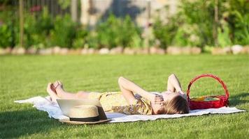 Young girl on a blanket in the grass with laptop and basket of fruit video