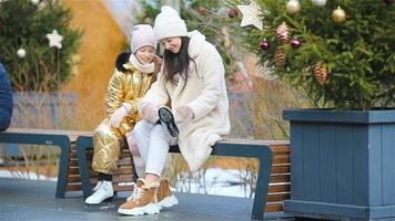 Adult woman and young girl together at outdoor ice skating rink