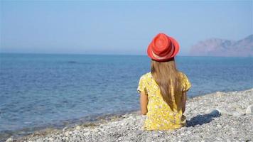 Young girl sitting on beach wearing pink hat video