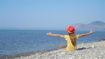 Young girl sitting on beach wearing pink hat video