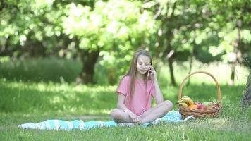 Jeune fille sur une couverture dans le herbe avec panier de fruit video