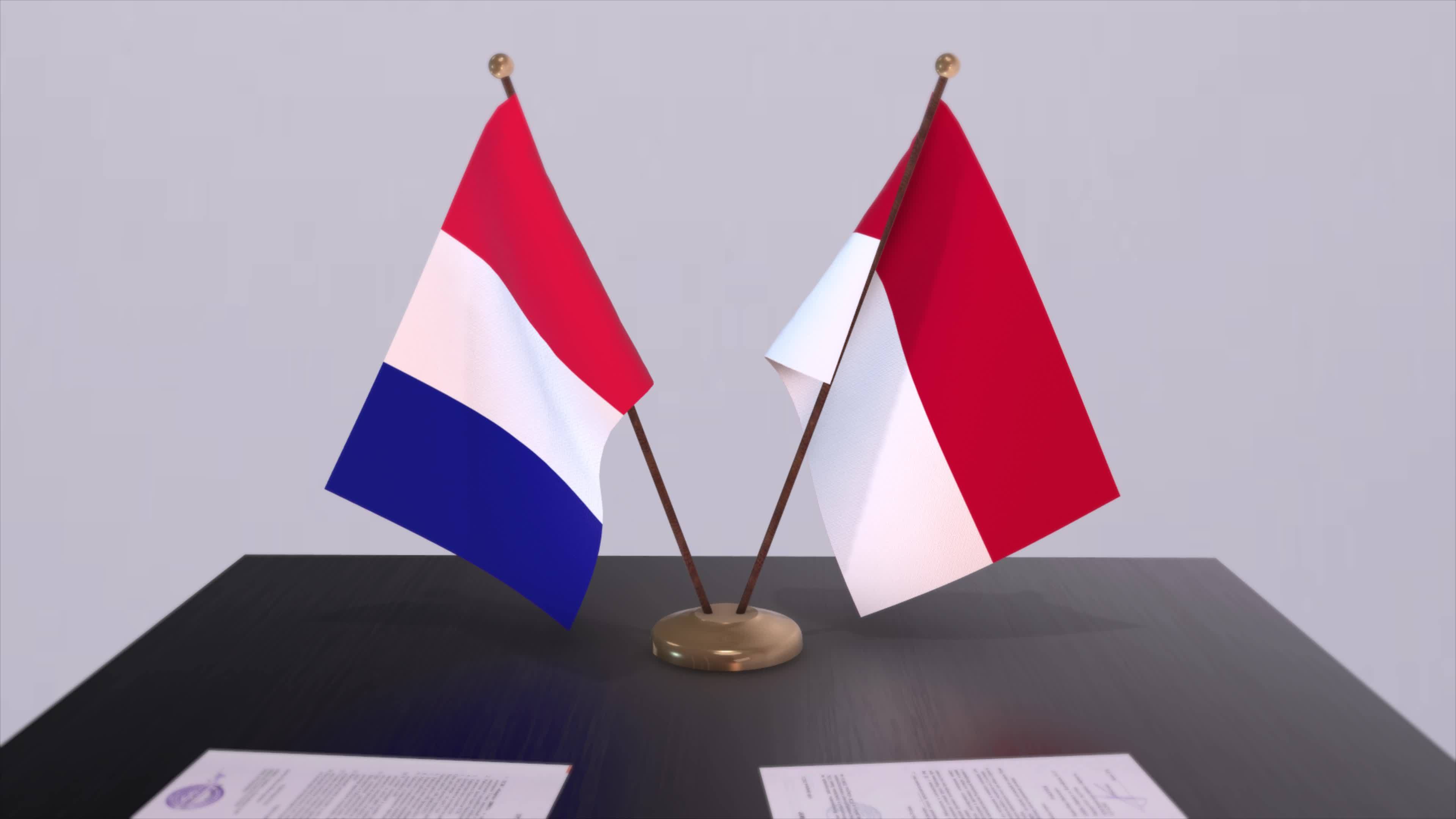 Monaco and France national flags on table in diplomatic conference room
