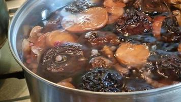 Preparation of dried fruit compote in a saucepan. Slow bubbling of boiling water and red currant berries, dried apples and pears. Stewed fruit. video