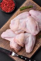 Raw chicken wings with salt, spices and herbs on a wooden cutting board photo