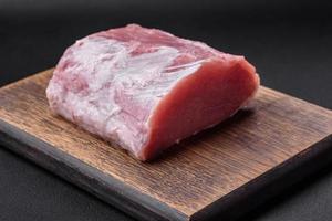 Fresh juicy pork on a wooden cutting board with spices and salt photo