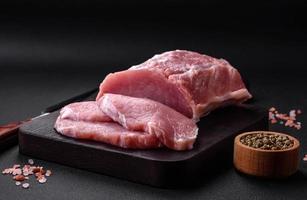 Fresh juicy pork on a wooden cutting board with spices and salt photo