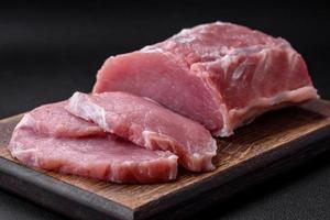 Fresh juicy pork on a wooden cutting board with spices and salt photo